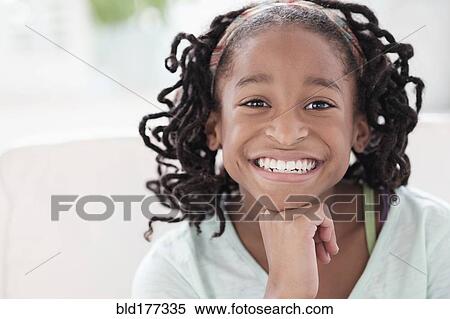 Stock Photography - Smiling Black girl resting chin in hand. Fotosearch