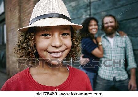 Stock Image - Smiling girl wearing fedora outdoors. Fotosearch