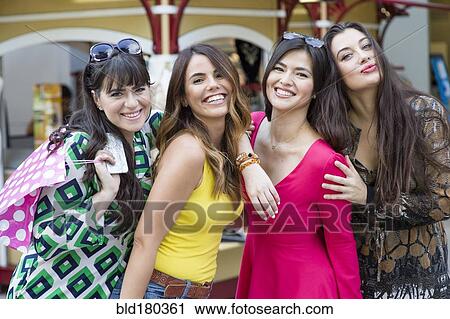 Stock Image - Smiling Hispanic women holding shopping bags. Fotosearch