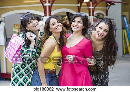 Stock Image - Smiling Hispanic women holding shopping bags. Fotosearch