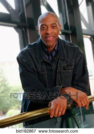 Smiling man leaning on banister View Large Photo Image Stock Photo - Smiling man leaning on banister. Fotosearch
