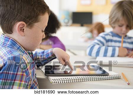 Stock Image - Student using digital tablet in classroom. Fotosearch