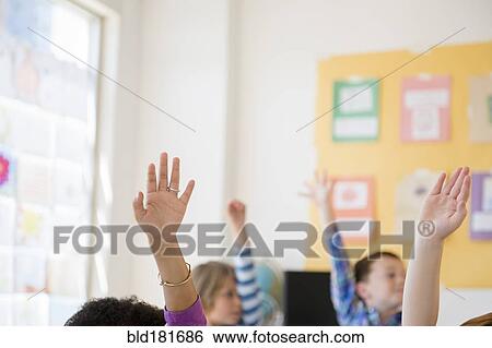 Stock Photograph - Students raising hands in classroom. Fotosearch