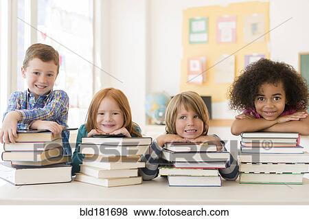 Stock Photo - Students resting on stacks of books in classroom. Fotosearch