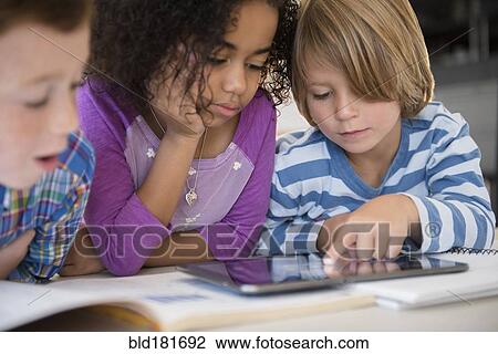 Stock Image - Students using digital tablet in classroom. Fotosearch