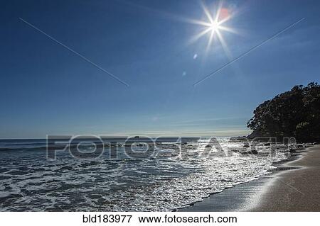 Stock Photo - Sun over horizon at remote beach. Fotosearch