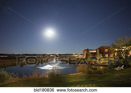 Stock Photograph - Sun rising over fountain in rural landscape. Fotosearch