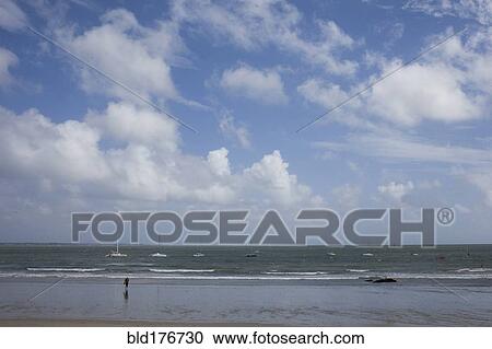 Tourist standing in waves on beach View Large Photo Image Stock Image - Tourist standing in waves on beach. Fotosearch