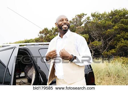 Well-dressed Black man outdoors near car View Large Photo Image Stock Photography - Well-dressed Black man outdoors near car. Fotosearch