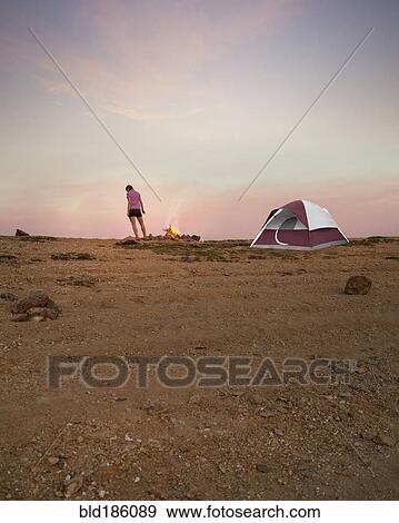 Stock Photo - Woman camping in remote desert field. Fotosearch