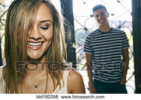 Stock Photograph - Woman laughing with boyfriend in background. Fotosearch