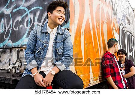 Picture - Woman listening to friends talking at graffiti truck. Fotosearch