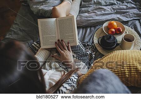 Stock Photo - Woman reading book on bed. Fotosearch