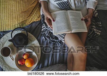 Stock Photograph - Woman reading book on bed. Fotosearch