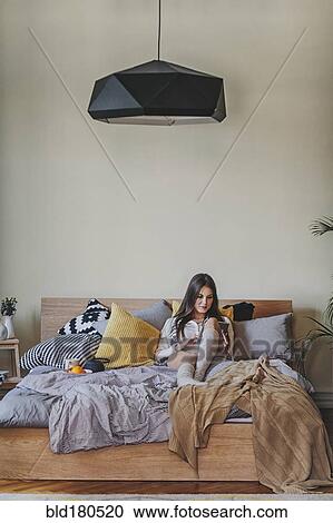 Stock Image - Woman reading digital tablet on bed. Fotosearch
