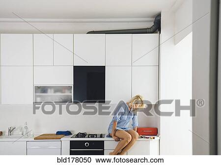 Woman reading on kitchen counter View Large Photo Image Stock Image - Woman reading on kitchen counter. Fotosearch