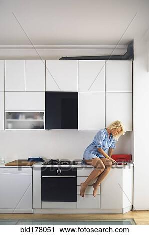 Woman reading on kitchen counter View Large Photo Image Stock Image - Woman reading on kitchen counter. Fotosearch