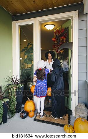 Woman receiving trick-or-treaters on Halloween View Large Photo Image Picture - Woman receiving trick-or-treaters on Halloween. Fotosearch
