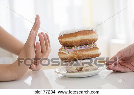Picture - Woman refusing plate of donuts. Fotosearch