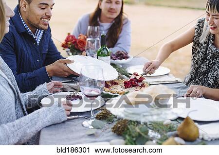Stock Image - Woman serving pie at outdoor table. Fotosearch