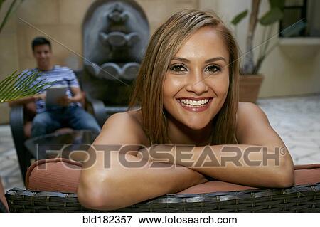 Stock Photo - Woman sitting on bench in courtyard. Fotosearch