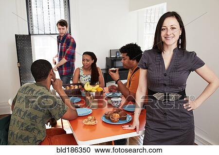 Stock Image - Woman smiling at table with friends. Fotosearch