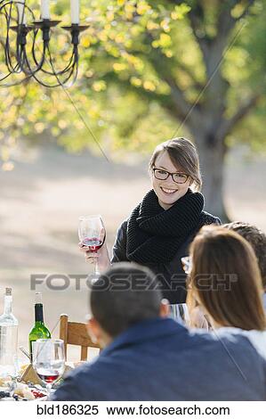 Woman toasting with wine at outdoor table View Large Photo Image Stock Photography - Woman toasting with wine at outdoor table. Fotosearch
