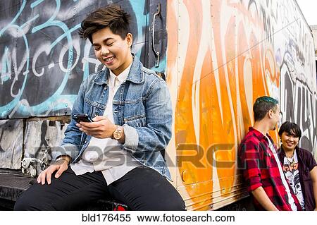 Stock Photography - Woman using cell phone at graffiti truck. Fotosearch