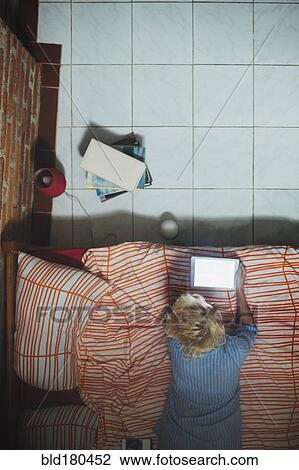 Stock Image - Woman using digital tablet on bed. Fotosearch