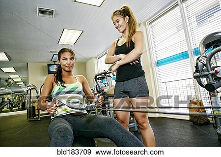 Stock Photo - Woman working out with trainer in gymnasium. Fotosearch