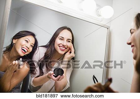 Stock Photo - Women applying makeup in mirror. Fotosearch