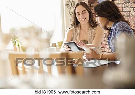 Stock Photography - Women using digital tablet in coffee shop. Fotosearch