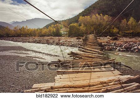 Stock Image - Wooden bridge over remote river. Fotosearch