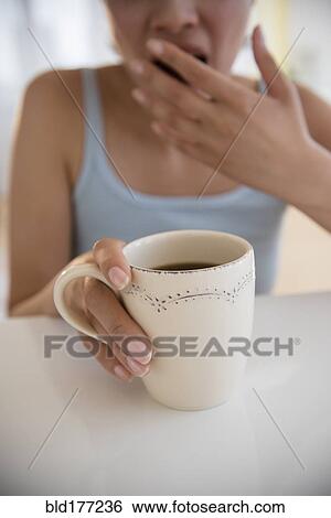 Yawning Hispanic woman drinking coffee View Large Photo Image Stock Photograph - Yawning Hispanic woman drinking coffee. Fotosearch