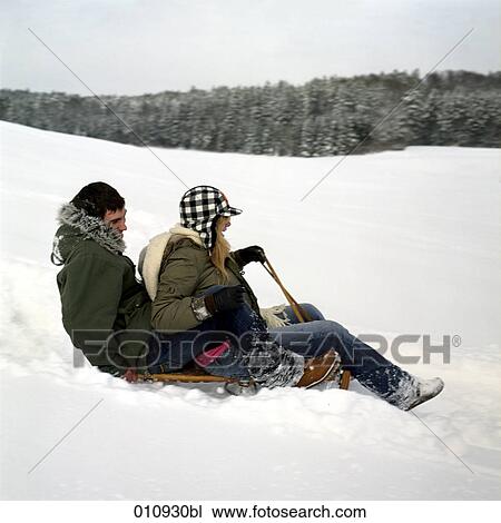 Stock Image - a teenage couple sledging. Fotosearch