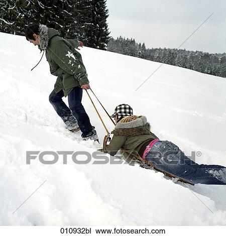 Stock Image - a teenage couple sledging. Fotosearch