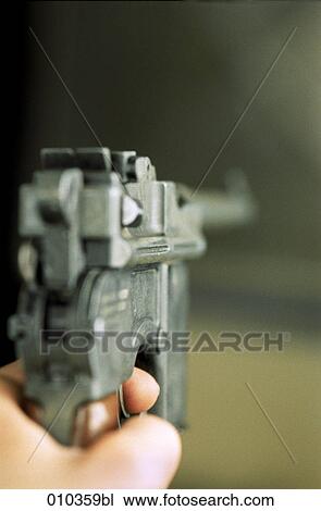 Stock Image - blurred close-up of hand holding a Mauser C96 pistol. Fotosearch