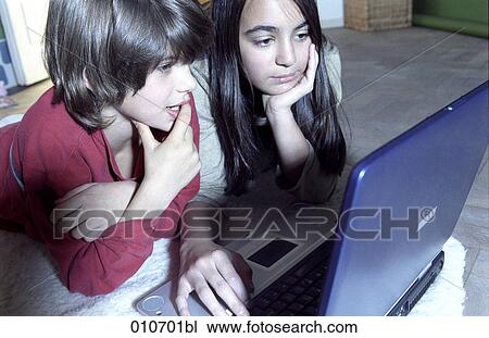 Stock Image - boy and girl lying on the floor and working with notebook computer. Fotosearch