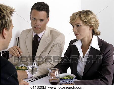 Stock Image - businessman and woman listening to colleague during lunch. Fotosearch