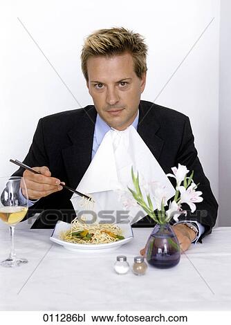 Stock Image - businessman with napkin eating noodles with chopsticks. Fotosearch