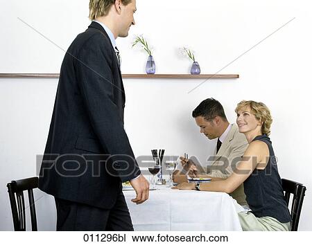 Stock Image - businessmen having lunch; woman glancing at man passing by. Fotosearch