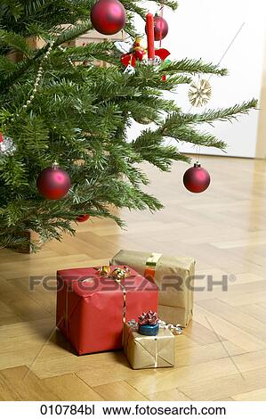 Stock Image - christmas presents on the floor under decorated christmas tree. Fotosearch