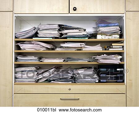 Stock Image - close up of filing cabinet with messy paper stacks. Fotosearch