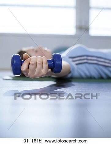 Stock Image - Close-up of teenage girl´s hand holding a dumb bell during exercise. Fotosearch
