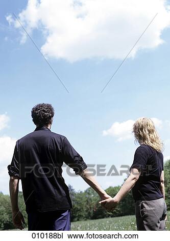 Stock Image - couple holding hands from behind. Fotosearch