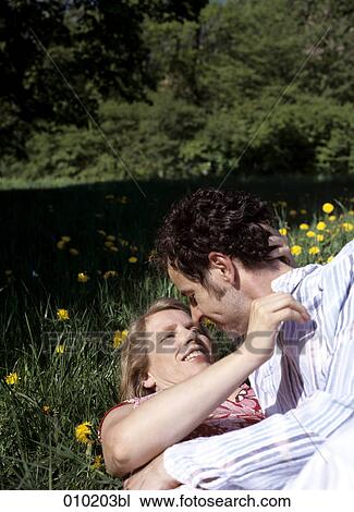 Stock Image - couple lying in the grass close to kissing each other. Fotosearch