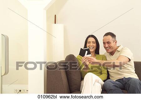 Couple on couch looking at photographs View Large Photo Image Stock Image - Couple on couch looking at photographs. Fotosearch
