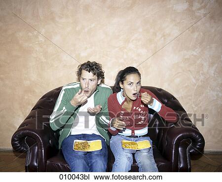 couple on leather sofa with Indian take-away food on their laps eating View Large Photo Image Stock Image - couple on leather sofa with Indian take-away food on their laps eating. Fotosearch
