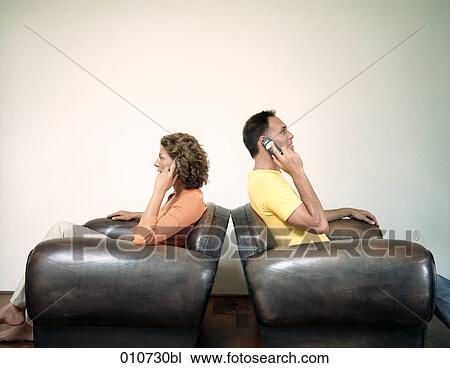 couple sitting back to back in arm chairs talking on mobile phones View Large Photo Image Stock Image - couple sitting back to back in arm chairs talking on mobile phones. Fotosearch