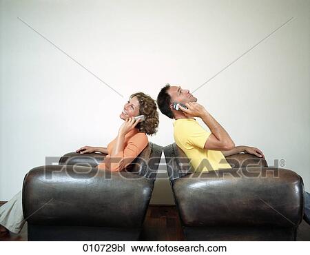 couple sitting in big leather arm chairs talking on mobile phones View Large Photo Image Stock Image - couple sitting in big leather arm chairs talking on mobile phones. Fotosearch